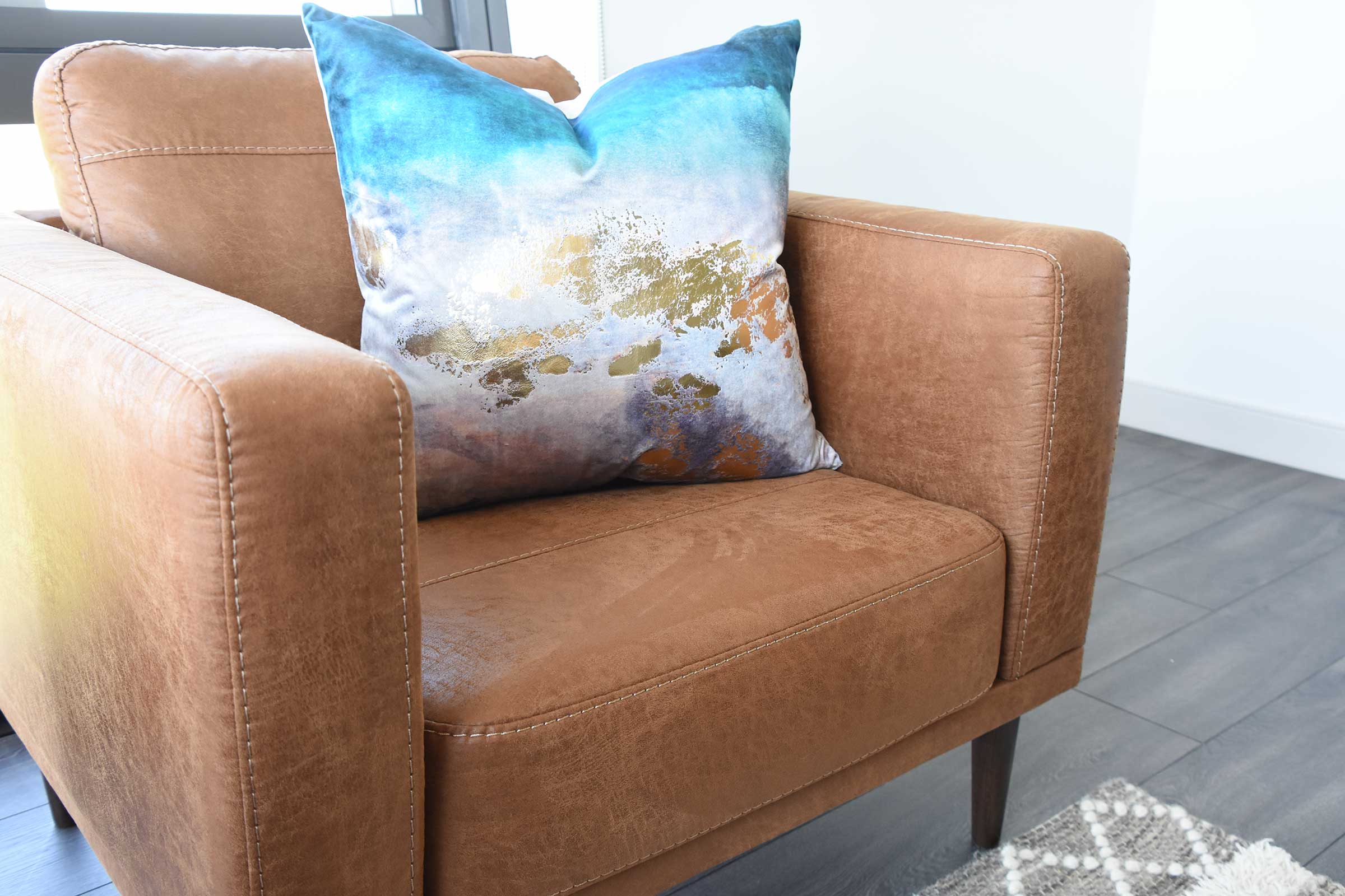brown leather chair with blue and gold accent pillow